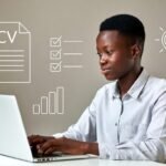 A confident young Kenyan professional working on a laptop at a clean desk, with subtle visual cues like a CV, checklist, or skills icons in the background.